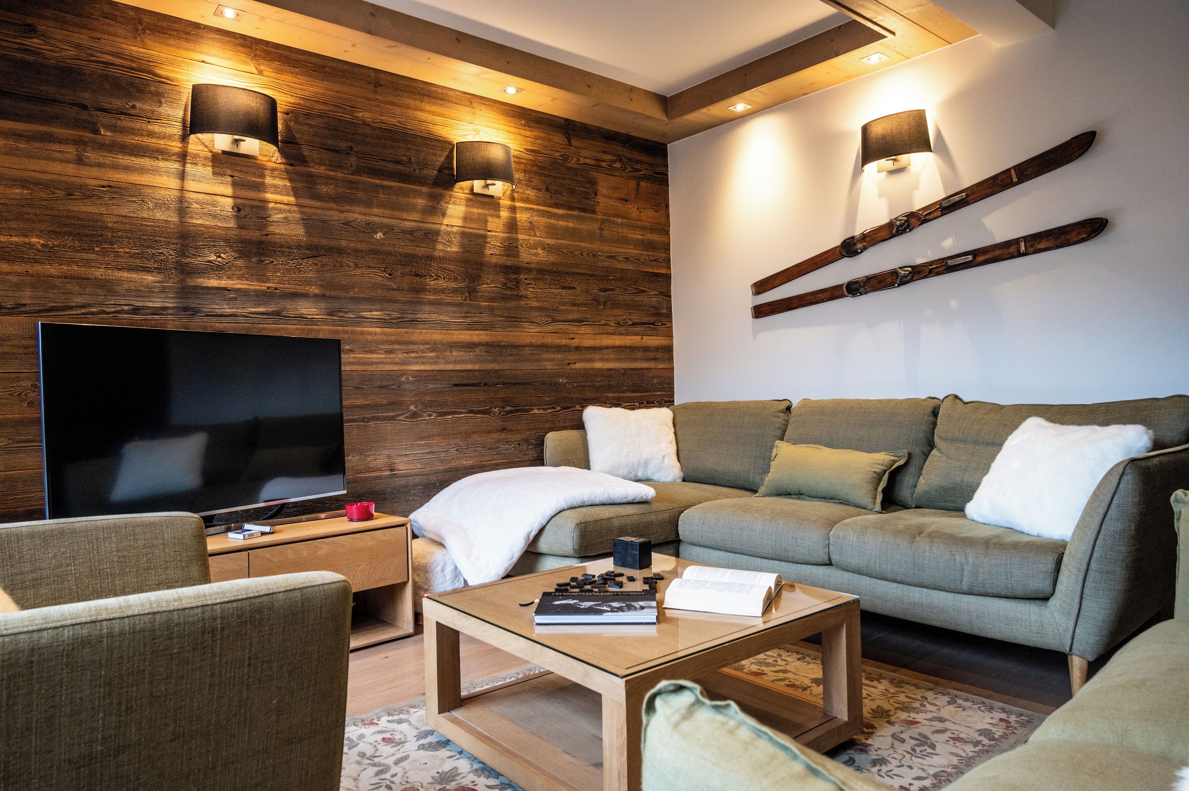 Una sala de estar moderna con un televisor de pantalla plana grande, una pared decorativa de madera y un sofá acogedor.