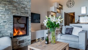 Una sala de estar moderna con chimenea de piedra, un sofá, una mesa de centro y un florero con flores.
