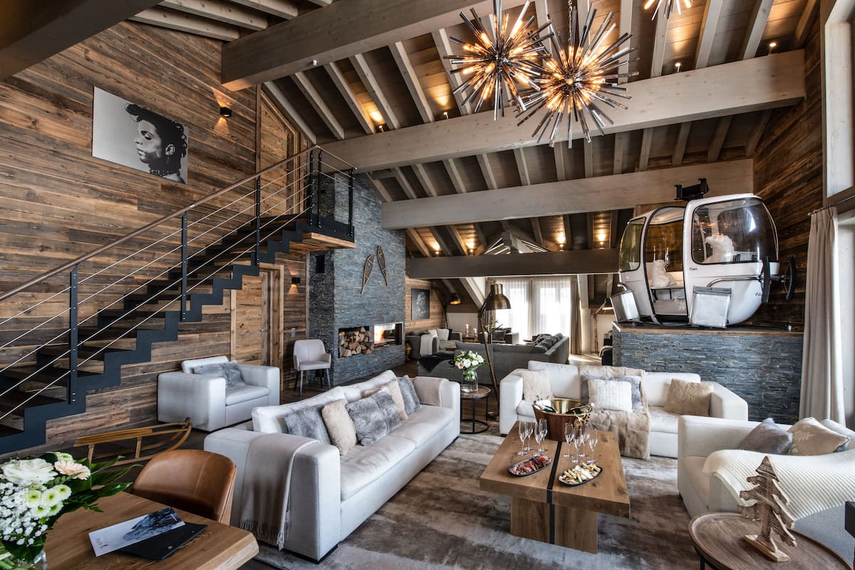 Ein großzügiger Wohnbereich mit modernem Design, inklusive einer Holztreppe, einem großen Sofa, einem Couchtisch und einer Pendelleuchte.