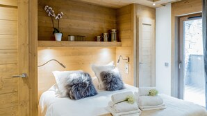 Un dormitorio con paneles de madera, una cama, almohadas, una mesita de noche y una ventana.