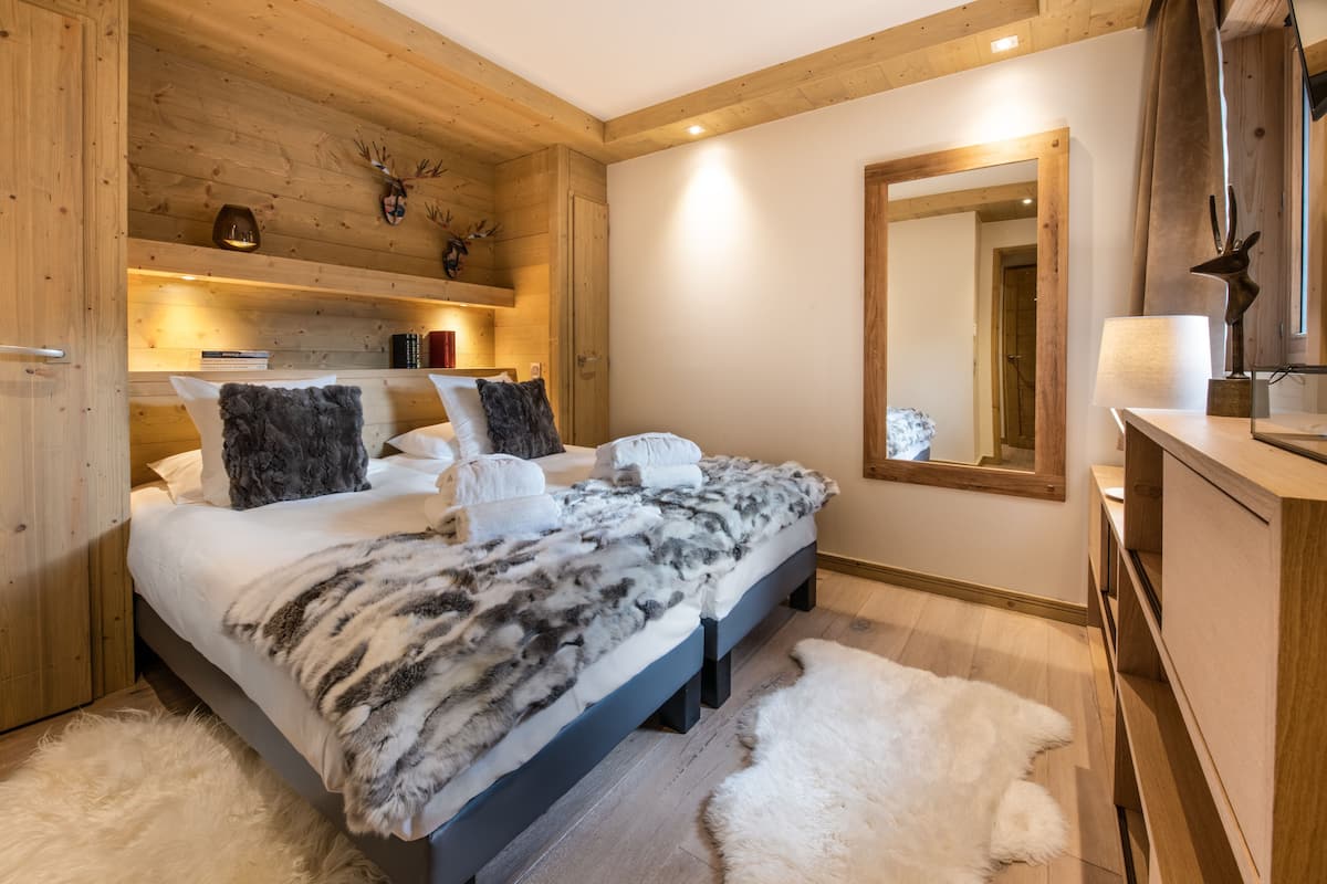 Ein Schlafzimmer mit Bett, Holz-Kopfteil, Spiegel, Kommode und Kamin.