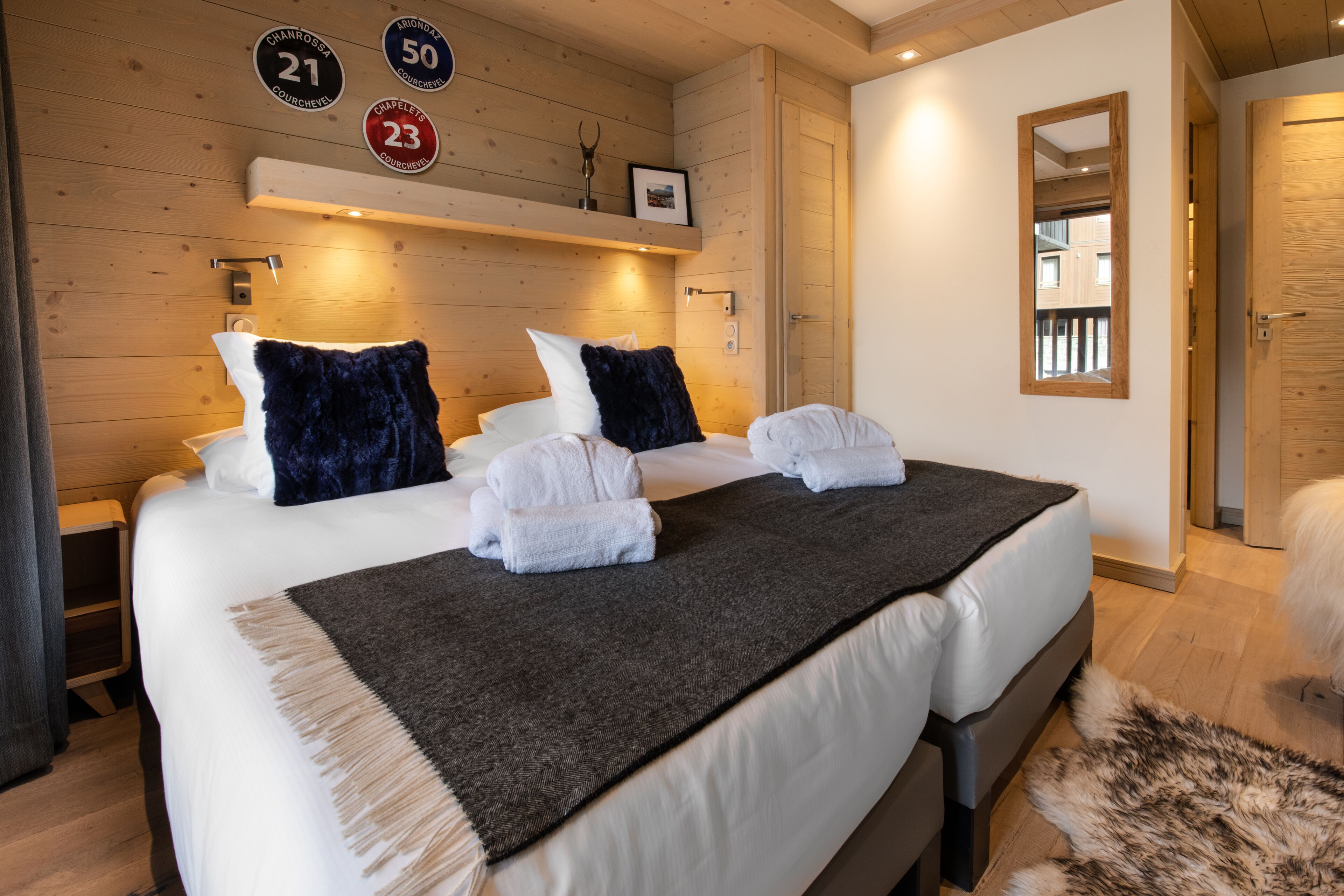A hotel room with a large bed, wooden walls, and a mirror.