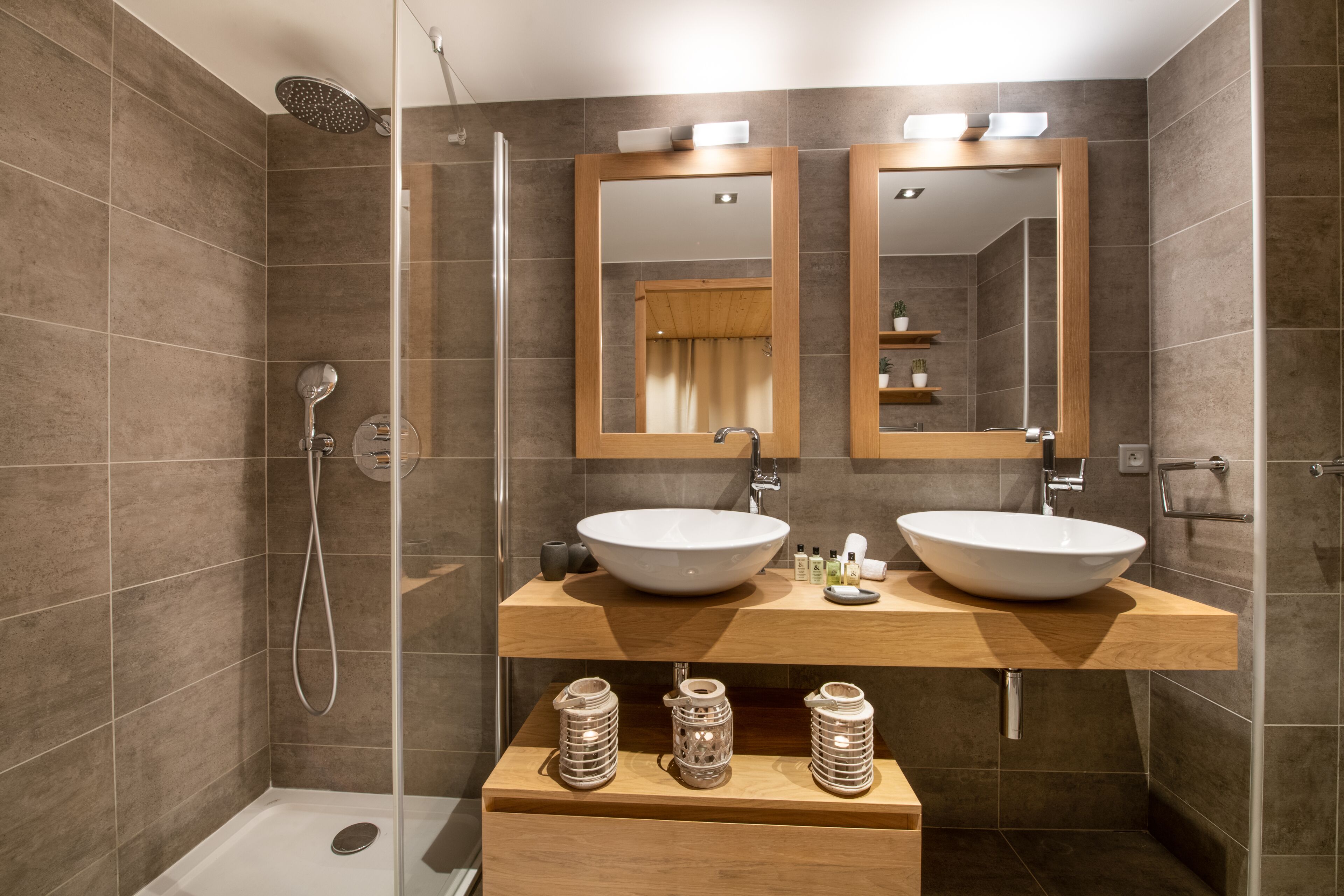Une salle de bain moderne avec deux vasques, une douche en verre et un meuble-lavabo en bois.