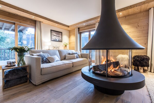 A cozy living room with a modern fireplace, a comfortable sofa, and a wooden floor.