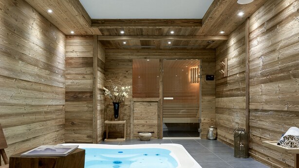 Een houten interieur met een jacuzzi, houten banken en een kleine tafel met een boek.