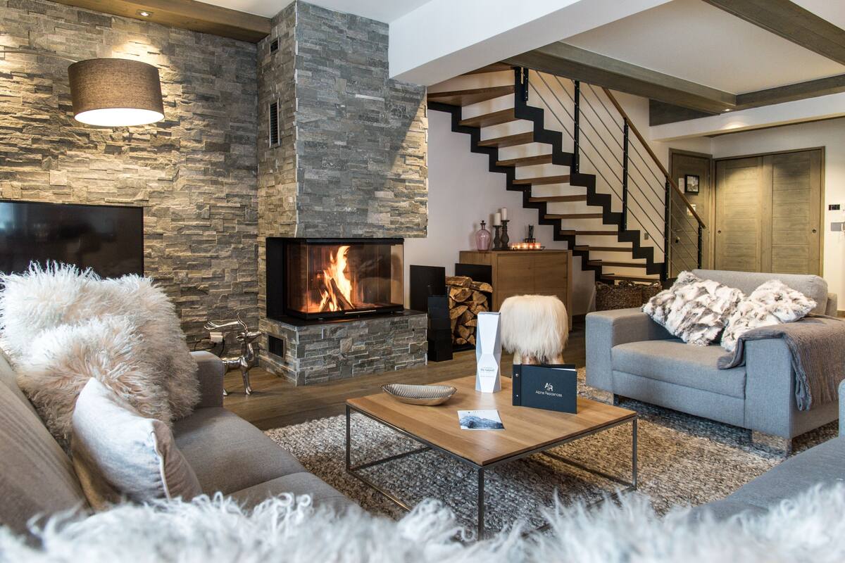 Una sala moderna con una chimenea de piedra, una escalera de madera y un sofá acogedor.
