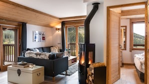 Een gezellige woonkamer met een open haard, een bank, een salontafel en uitzicht op de omgeving.