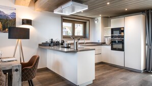 A modern kitchen with a central island, built-in appliances, and a large window.