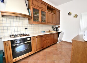 Una cocina con armarios de madera, horno empotrado, estufa a gas y lavavajillas.