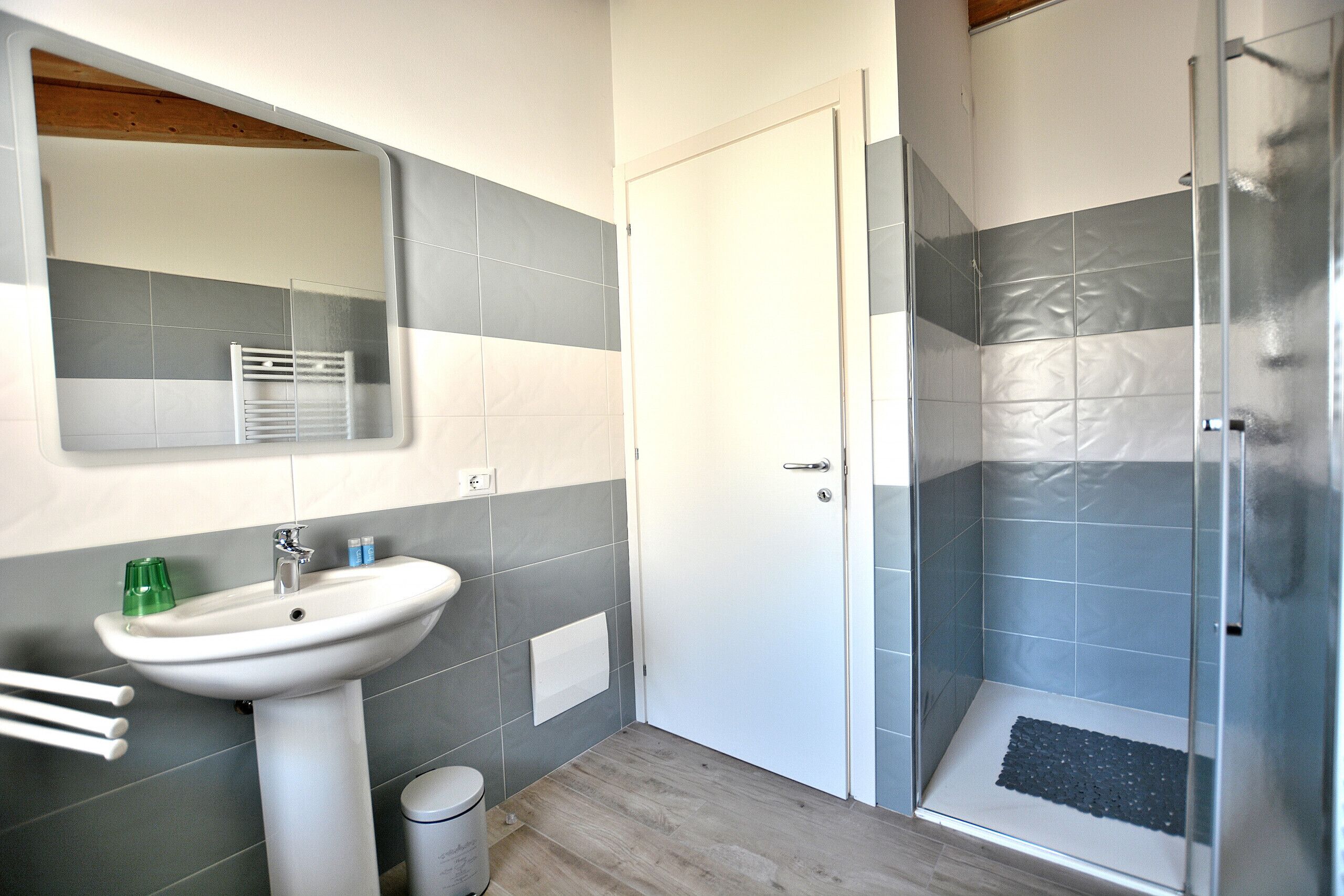 A bathroom with a sink, mirror, and shower.