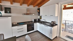 Une cuisine moderne avec des meubles blancs, un plan de travail noir, une cuisinière, un four à micro-ondes et un évier.