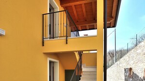 Un bâtiment à deux étages, à la façade jaune, doté d’un balcon en bois et d’un escalier menant à l’étage supérieur.