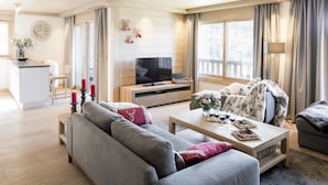 A modern living room with a grey sofa, a wooden coffee table, and a television. - Aspen Lodge by Alpine resorts (Courchevel)