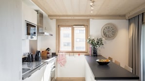 A modern kitchen with a central island, built-in appliances, and a large window. - Aspen Lodge by Alpine resorts (Courchevel)