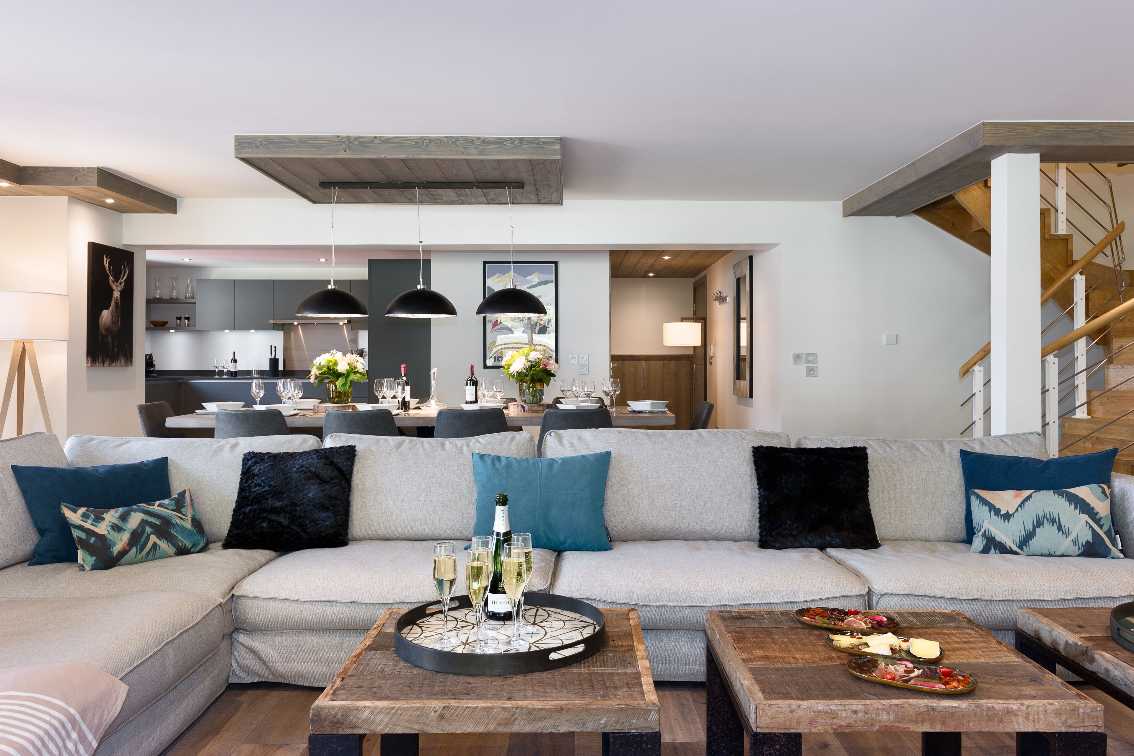 A modern living room with a sectional sofa, wooden coffee tables, and a dining area in the background.
