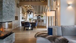 A modern interior with a stone fireplace, a dining area, and a living room with a sofa and fur throw.