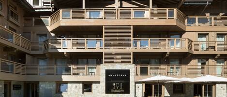A multi-story building with balconies, outdoor seating, and a sign for "Annapurna Vina Annapurna."