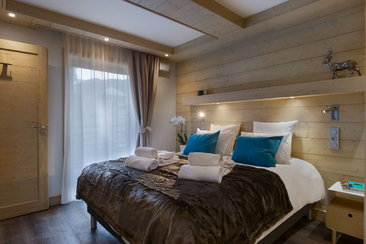 A bedroom with a wooden headboard, a bed with white and blue pillows, and a nightstand with a lamp.