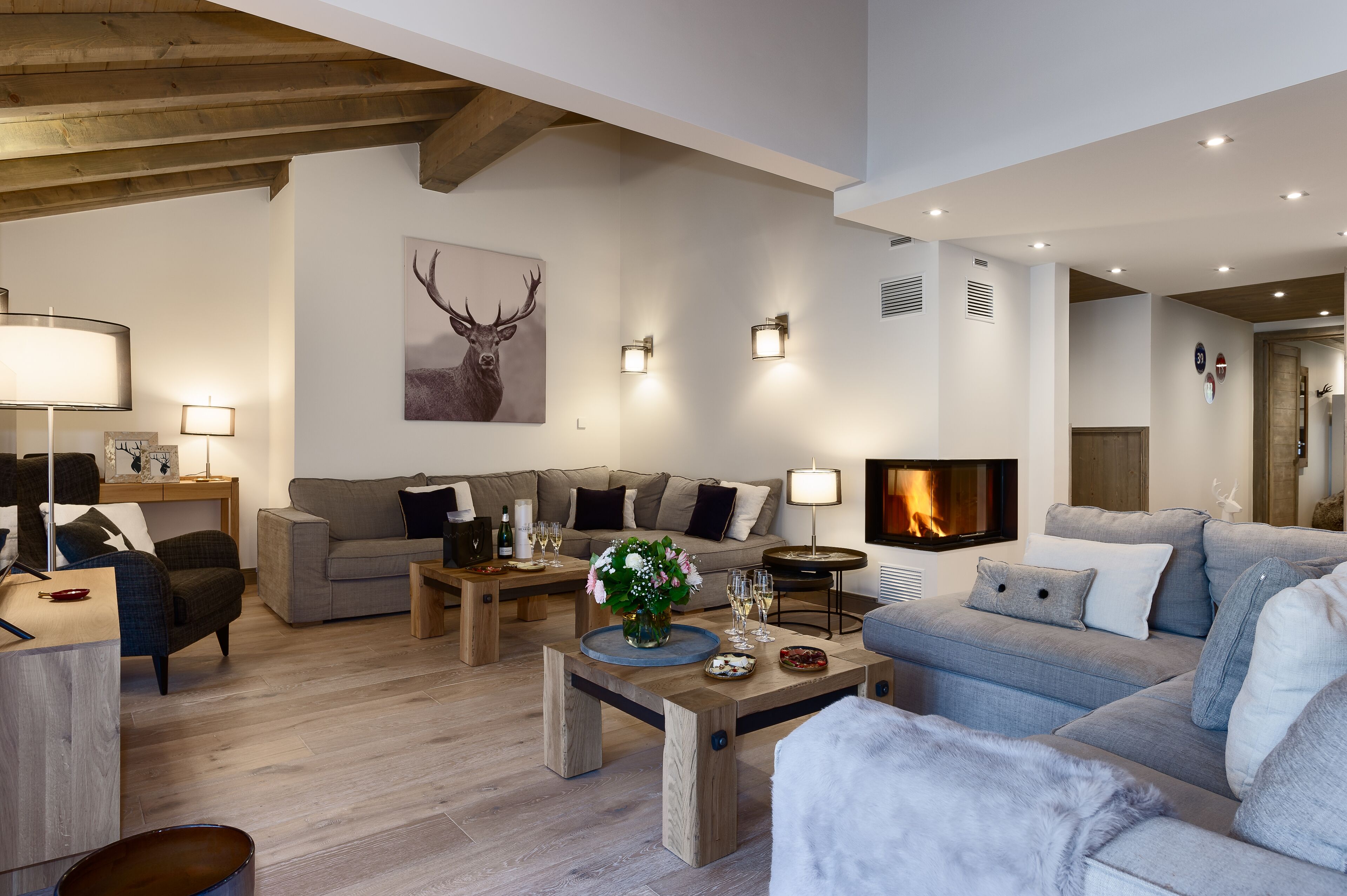 A modern living room with a fireplace, wooden beams, and a large sofa.