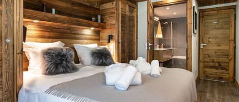 A wooden-paneled bedroom with a bed, pillows, and rolled towels.