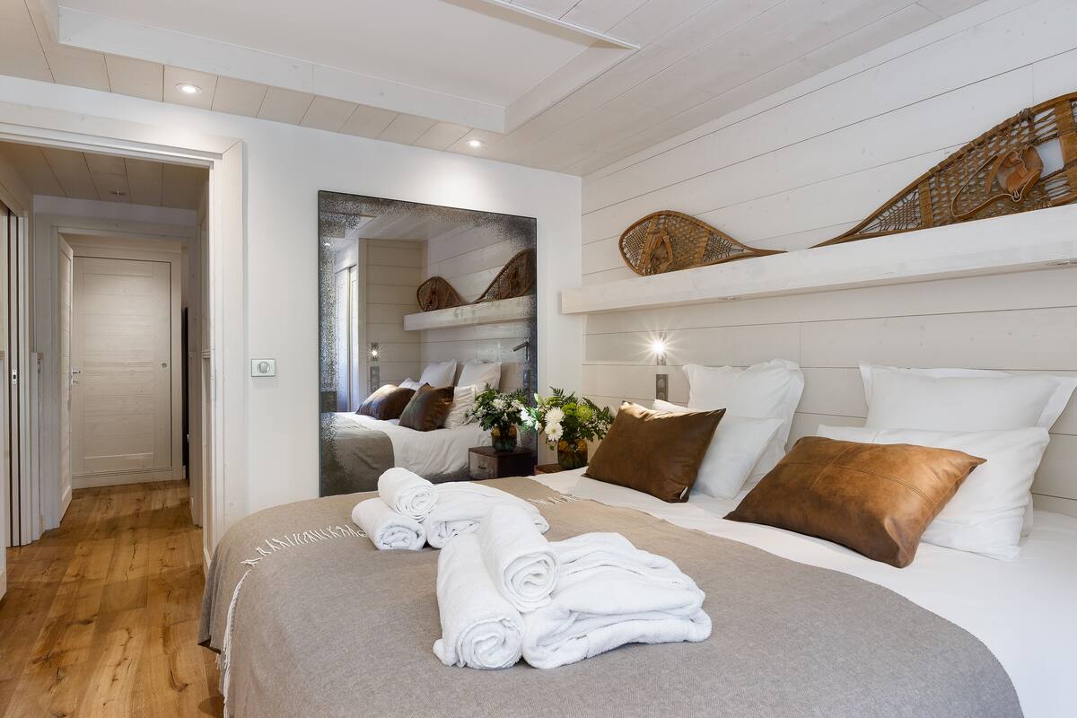 A hotel room with a large bed, a mirror, and a wooden floor.