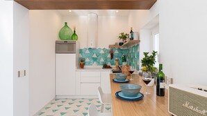 A modern kitchen with white cabinets, a wooden countertop, and a backsplash with geometric tiles.