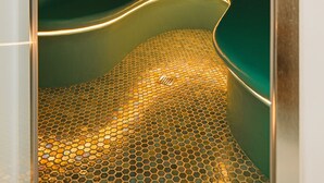 A spa room with a curved bench, a shower area, and a ceiling light.