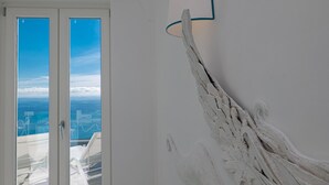 A room with a large window, a white wall, and a white textured sculpture.