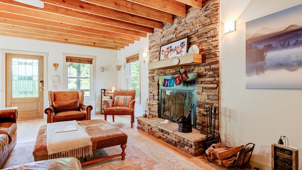 Una sala de estar acogedora con chimenea de piedra, vigas de madera y asientos cómodos.