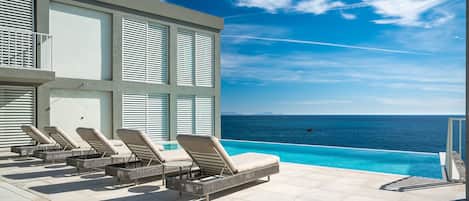 Una piscina al aire libre, sombrillas, sillones reclinables de piscina