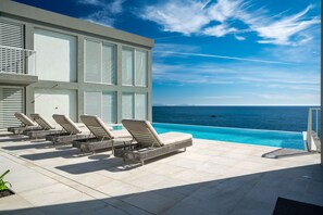 Un bâtiment moderne doté d’une piscine et de chaises longues.