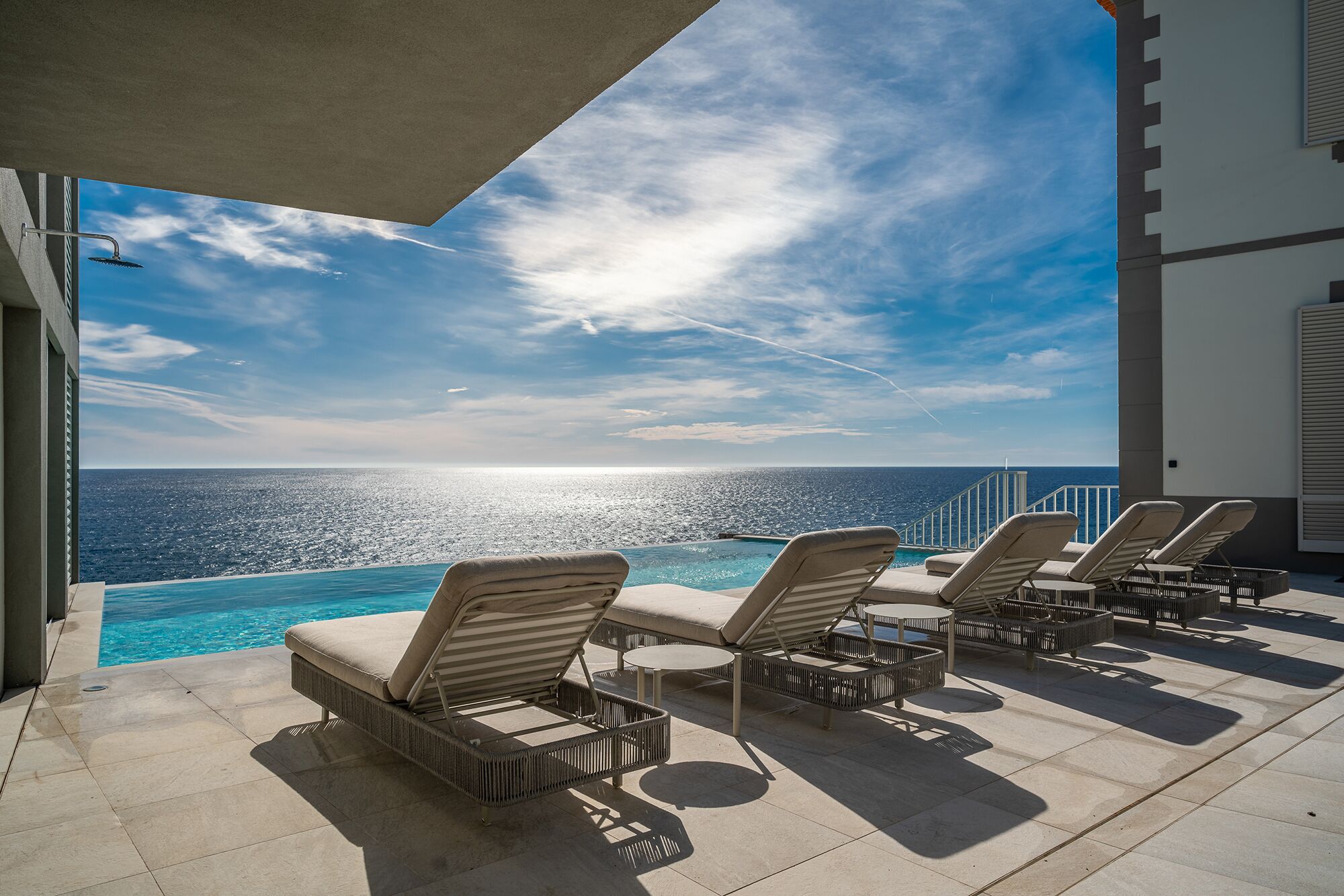 A poolside area with lounge chairs and a view of the ocean.
