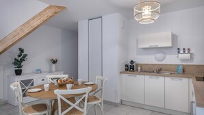 Une cuisine moderne avec des meubles blancs, une table à manger en bois et des chaises blanches.