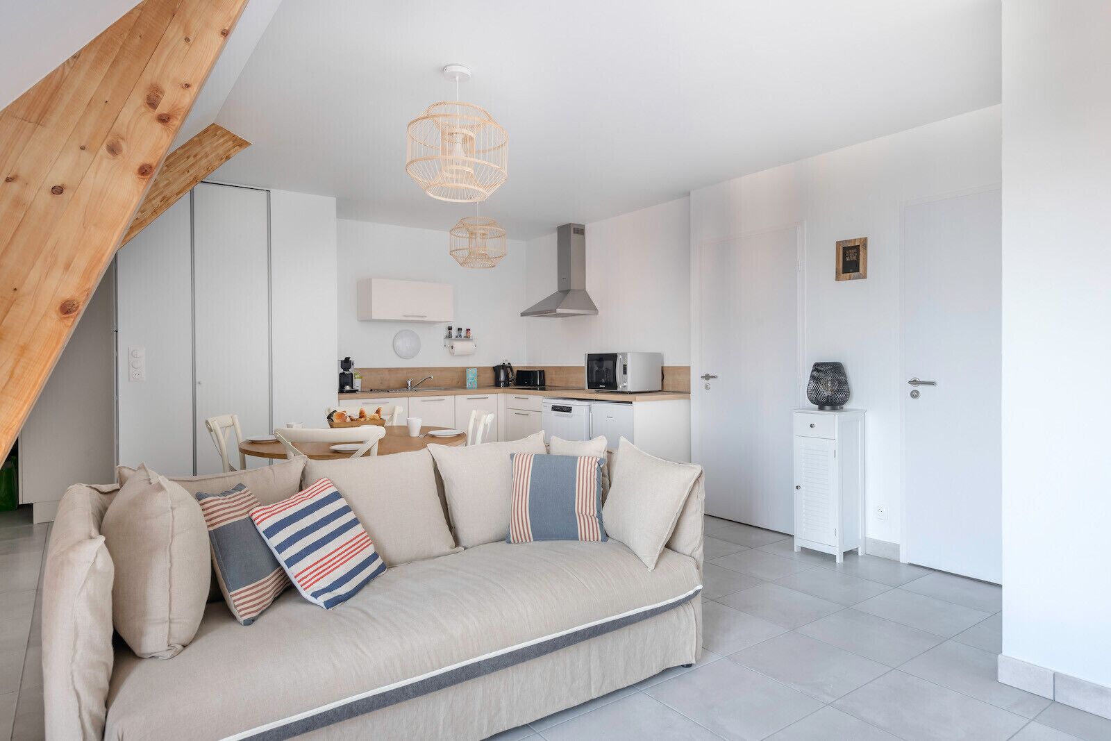 Una sala moderna con un sofá, una mesa de comedor y una cocina al fondo.