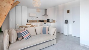 Un salon moderne avec un canapé, une table à manger et une cuisine en arrière-plan.