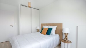 Une chambre à coucher moderne avec un grand lit, une tête de lit en bois et deux tables de chevet avec des lampes.