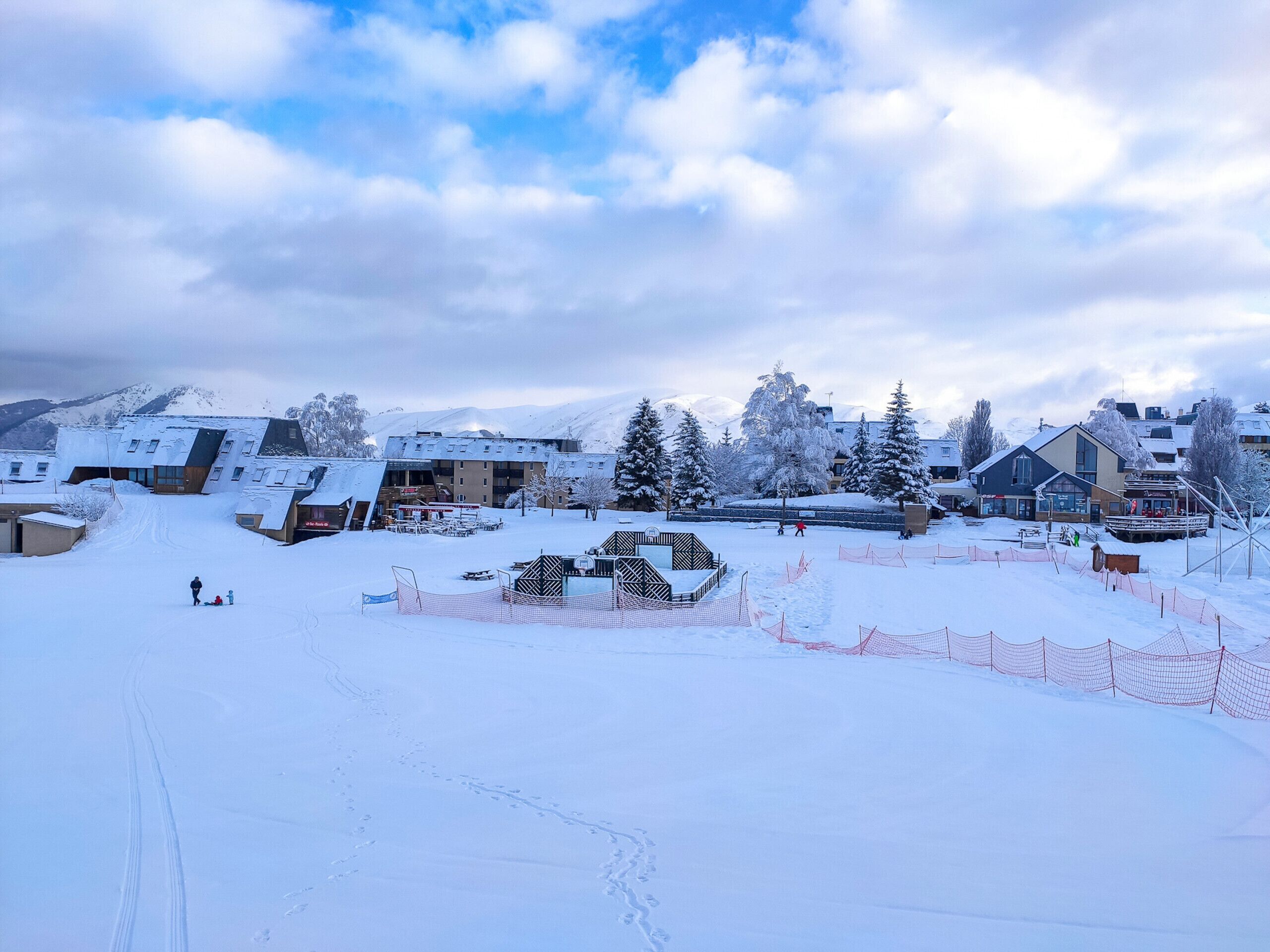 A snow-covered ski resort with buildings, a ski lift, and a snowy landscape.