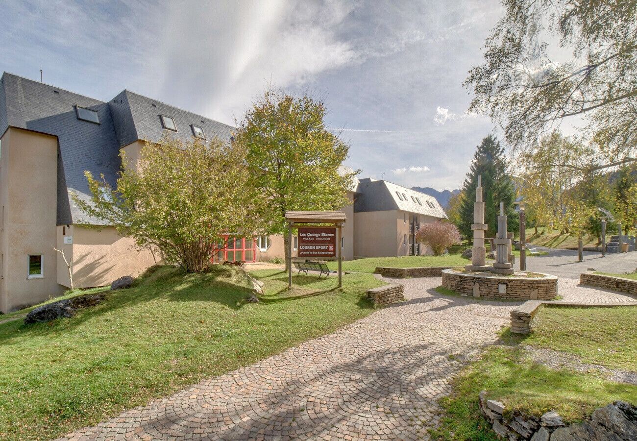 A building with a paved entrance, a signboard, and a stone monument in the center.
