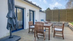 Un patio al aire libre con mesa y sillas de madera, una sombrilla y un muro de piedra.