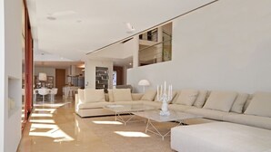 Un amplio salón con un sofá grande, una mesa de centro y una mesa de comedor.
