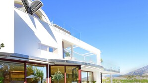 Un área de comedor exterior moderna con piscina, con vistas a un paisaje montañoso.