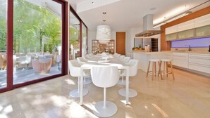 Una cocina moderna con armarios blancos, una isla grande y vistas al exterior a través de amplios ventanales.