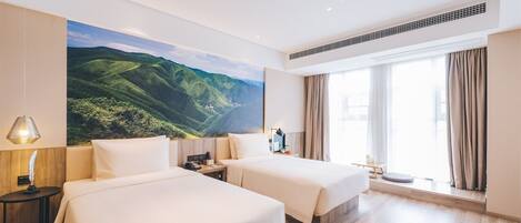 Habitación de hotel con dos camas, un ventanal con cortinas, un cuadro de un paisaje montañoso y un respiradero en el techo.