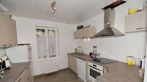 Ett modernt kök med vita skåp, en inbyggd ugn, en diskmaskin och ett fönster med utsikt över grönområden.