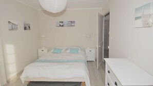 Ett sovrum med en säng, sängbord, en vit byrå och konst på väggen.