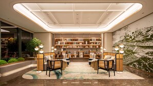 A modern lobby with a central seating area, a large bookshelf, and a decorative wall mural.