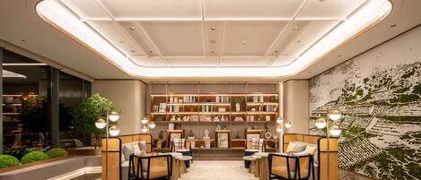 A modern lobby with a central seating area, a large bookshelf, and a decorative wall mural.