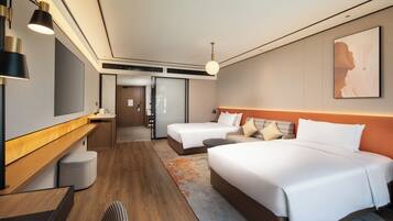 A hotel room with a large bed, a smaller bed, a desk, and a chair. There is a mirror on the wall and a painting above the bed.