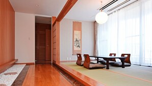 Una habitació japonesa tradicional amb tatami, una taula baixa amb coixins i portes corredisses.