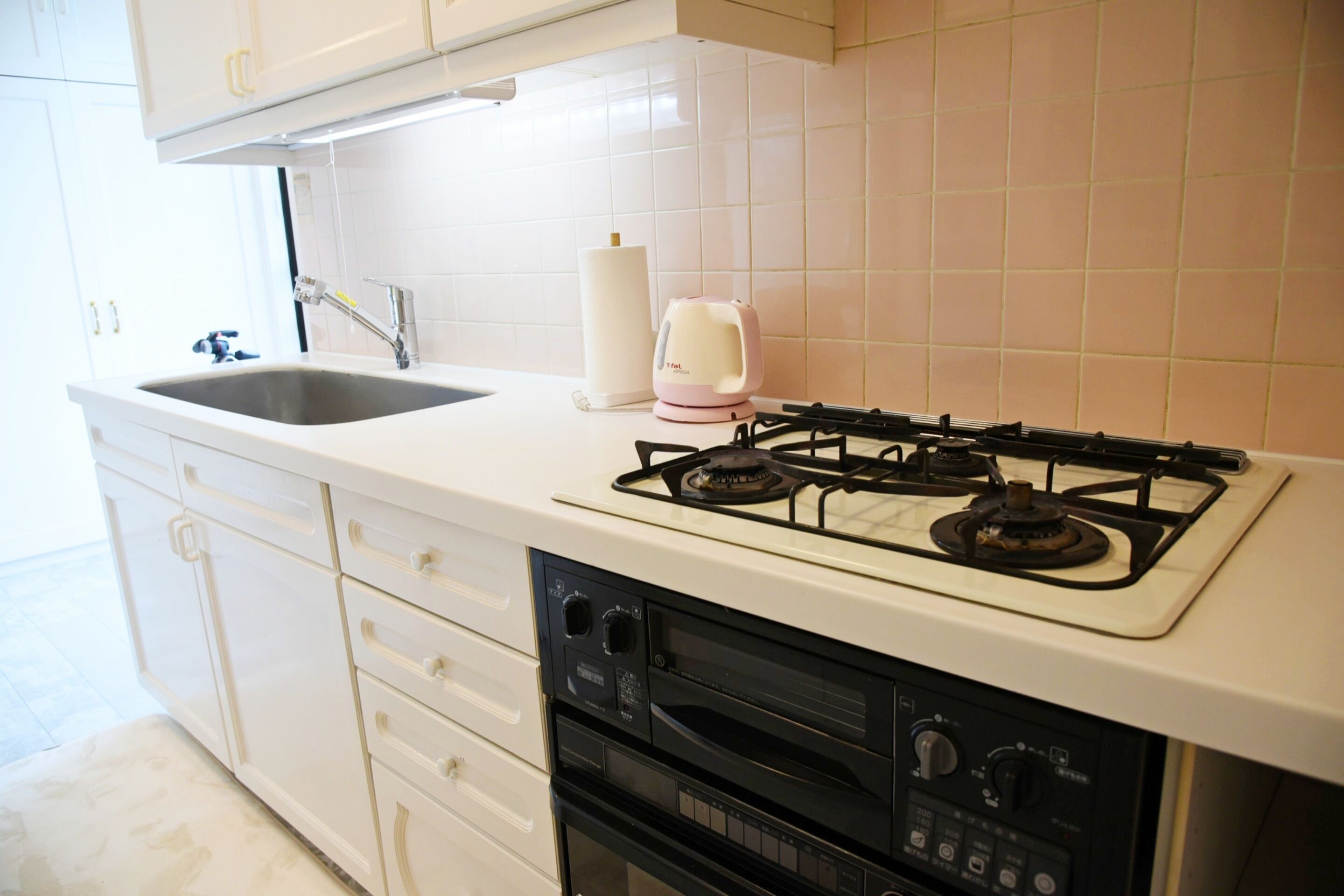A kitchen with a white countertop, a gas stove, a built-in oven, and a sink.